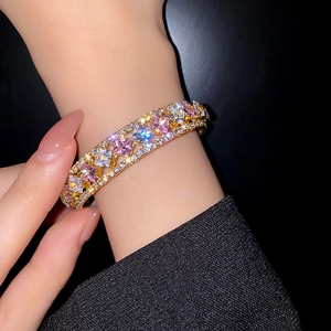 Nahaufnahme des goldenen hohlen Armreifs mit großen bunten Zirkonia und Seiten-Diamanten