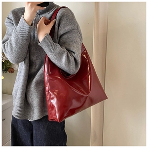 Large red leather underarm bag worn by model over a grey sweater for casual style