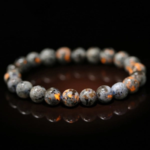 Grey flame stone beaded bracelet with vibrant orange spots on a black reflective surface