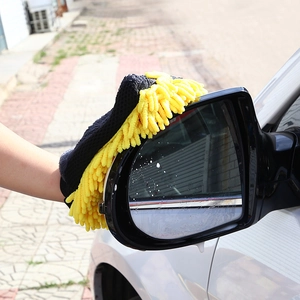 Action shot of yellow chenille wash mitt cleaning a black car side mirror