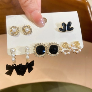 Close-up of five pairs of vintage floral and pearl earrings on a white display card