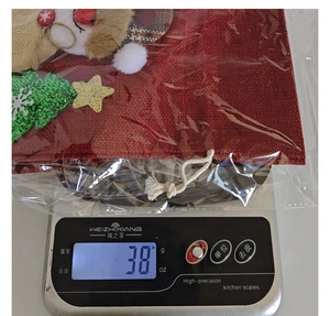 Christmas burlap wine gift bag being weighed on a digital kitchen scale showing 38g.