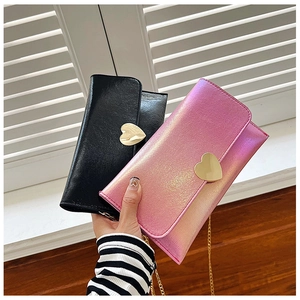 Detail of elegant chain wallets with golden heart clasps in black and iridescent pink