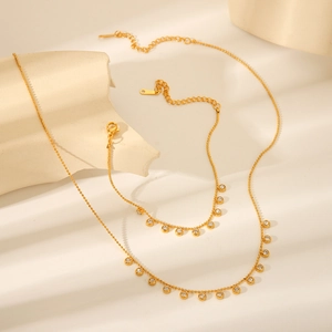 Detail of gold-plated stainless steel necklace and bracelet set with white zircon stones