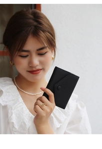 Close-up of black lychee grain leather wallet with envelope flap held by model