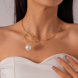Close-up of golden metal collar necklace featuring a large baroque pearl pendant for women
