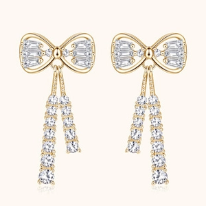 Detail of elegant gold bow earrings with crystal tassels and sparkling moissanite gems