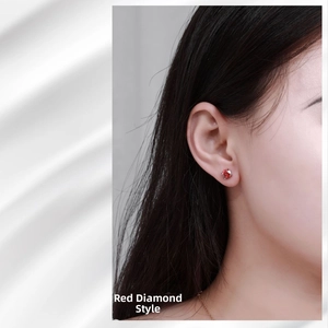 Close-up of a sterling silver ear stud with a four-prong set round red gemstone on model