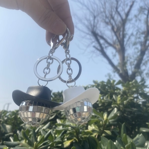 Nahaufnahme von Disco-Kugel-Schlüsselanhängern mit Mini-Cowboyhüten in Schwarz-Weiß