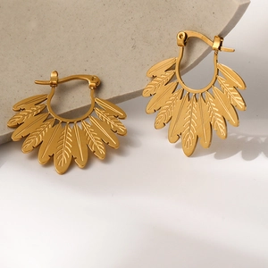 Elegant gold leaf shape feather earrings with bohemian style on a stone background
