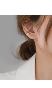 Detail view of a sparkling gold star ear cuff with zircon stones worn by a model