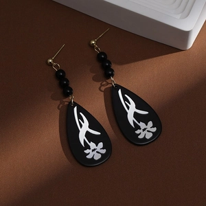 Detail of Chinese style fan-shaped earrings with black floral pearls and golden tassels