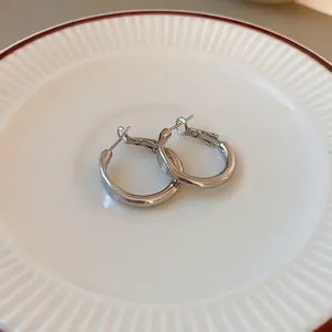 Minimalist silver hoop earrings in S925 sterling silver style on white ceramic plate