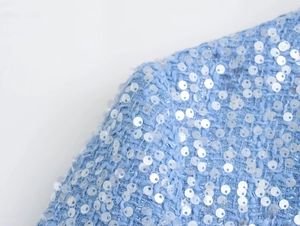 Macro view of light blue tweed fabric with shimmering silver sequins on the jacket