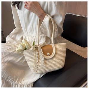 Detail of straw woven bag with brown leather flap, pearl clasp and lace ribbon