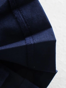 Detailansicht eines dunkelblauen Faltenrocks aus Twill-Stoff mit verstärkten Doppelsteppnähten