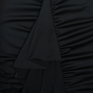 Gros plan détaillé montrant le froncement noir texturé et le tissu plissé de la robe