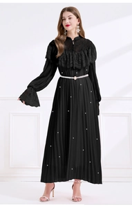Détails de l'encolure en dentelle et de la ceinture de perles sur la robe plissée noire