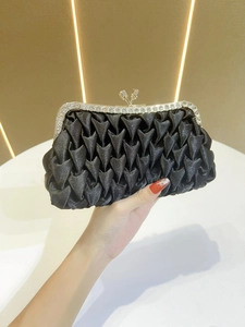 Dettaglio della pochette da sera in raso nero con texture a pieghe e strass