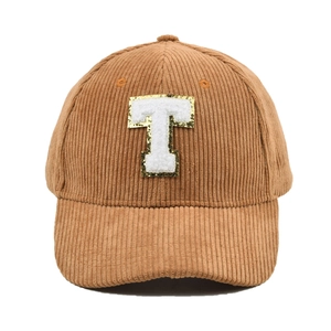Nahaufnahme der braunen Cord-Baseballkappe mit einem weißen T-Buchstaben-Aufnäher.