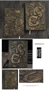 Macro detail of antique bronze embossed dragon notebook showing texture and 3D reliefs