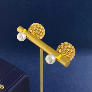 Elegant gold hollowed crystal earrings with white pearls on a blue background