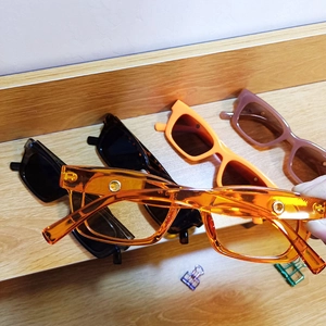 Detailed pile of colorful retro square frame sunglasses on a rustic wooden table