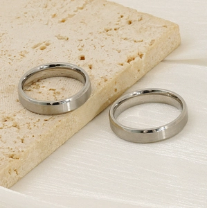 Detail of silver brushed titanium steel rings on travertine stone and white silk fabric