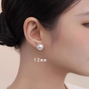 Detailed view of a model wearing a 12mm white pearl stud earring with soft metallic luster