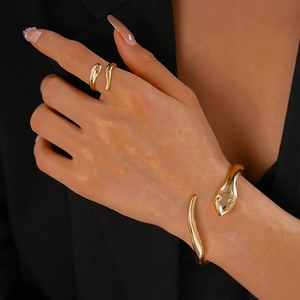 Detailed macro view of gold snake-shaped open bracelet and ring with mirror-polished finish