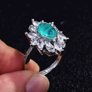 Macro detail of emerald style halo ring with oval green stone and zircon petal accents