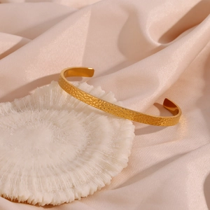 Minimalist 18K gold-plated stainless steel hammered cuff bracelet on beige silk