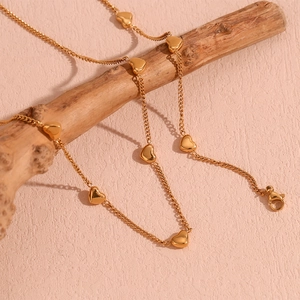 Detailed view of 18K gold plated heart pendant necklace on a natural wooden branch