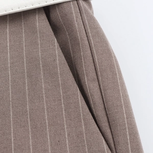 Close-up of brown pinstripe suit pants with fine fabric texture and white belt detail