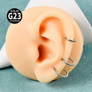 Macro detail of G23 titanium septum ring with white opal inlay shown on ear model