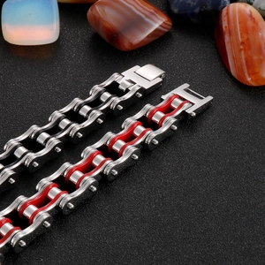 Detail of silver-black and silver-red motorcycle chain bracelets on a dark textured surface