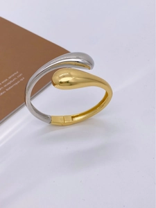 Detailed side view of a bicolor teardrop open bangle with gold and silver polished finish