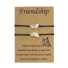 Detail of two butterfly friendship bracelets with gold accents on a brown kraft card