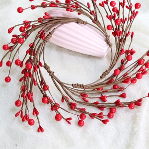 Close-up of a festive red berry wreath on a textured ceramic vase for home decoration