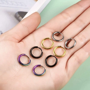 Detail shot of mini stainless steel hoop earrings in various colors held in hand