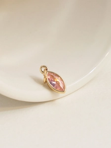 Macro detail of 18K gold plated necklace pendant with a pink marquise-cut zircon stone