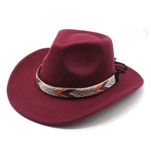 Chapeau de cow-boy vintage en feutre bordeaux avec bandeau ethnique et gland sur blanc