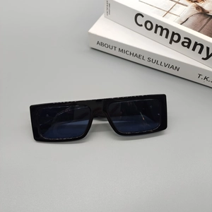 Close-up of black rectangular retro sunglasses with glossy finish on aesthetic books