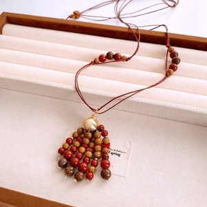 Macro detail of red and brown beaded necklace with a gold accent on a jewelry tray