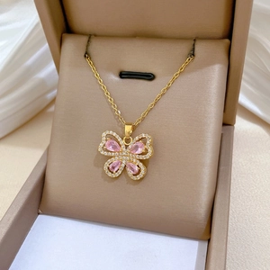 Close-up of golden butterfly pendant with pink pear-shaped gemstones and pavé crystals