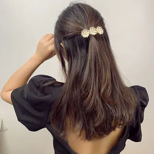 Detail of floral lace hair clip with white pearls worn on semi-tied hairstyle