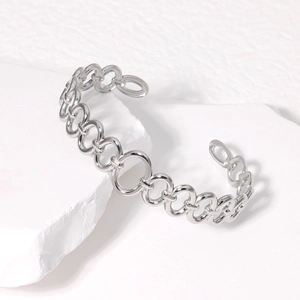 Silver chain-link open cuff bracelet in stainless steel on white textured stone