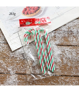 Detail of Christmas candy cane ornaments with red green stripes on snowy wood background
