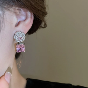 Close-up of camellia earrings with silver plating, small diamonds and pink square gems