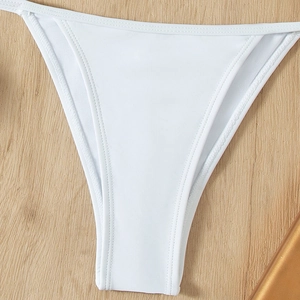 White ribbed bikini bottoms with side straps on light wood background for women
